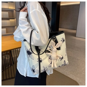 Floral canvas tote bag detail with black straps and cute rabbit plush pendant accessory