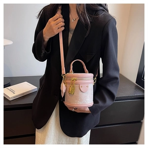 Detail of pink mini bucket bag featuring gold lock and detachable crossbody strap
