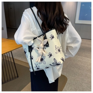 Detail of canvas tote bag with black floral print and cute rabbit pendant on shoulder strap