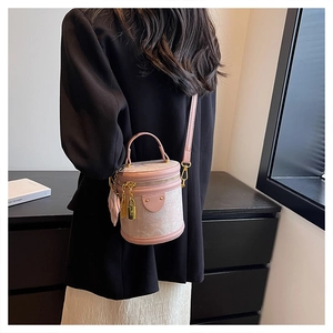 Detail of pink cylindrical bucket bag with embossed patterns and gold hardware accents