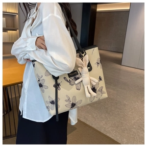 Detail of canvas tote bag with black floral pattern and cute plush bunny pendant accessory