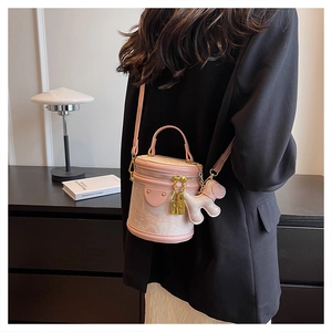 Detailed view of pink cylindrical mini bucket bag with puppy charm and gold hardware