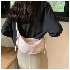 Detail of light pink jacquard half-moon bag with textured fabric and beaded pendant