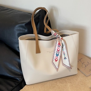 Minimalist beige tote bag with brown handles and decorative patterned silk scarf