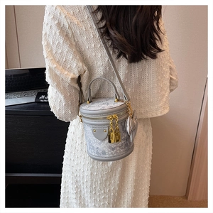 Detailed view of mini grey cylinder bucket bag with leather trim and gold padlock hardware