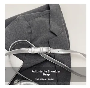 Detail view of a metallic silver adjustable shoulder strap with metal buckle on a grey suit