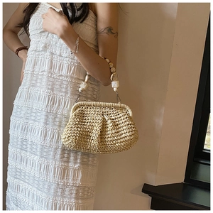 Detail of woven straw handbag featuring beaded handle and vintage metal frame closure