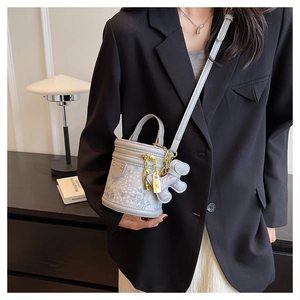 Detail of light blue bucket bag with floral texture, bear charm, and gold padlock detail