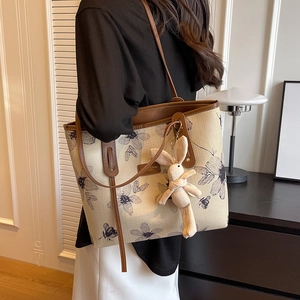 Canvas tote bag with blue floral print and brown leather straps worn on the shoulder