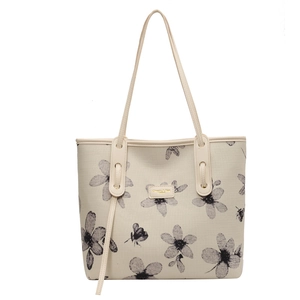 Cream canvas tote bag with black floral and bee prints featuring thin dual shoulder straps