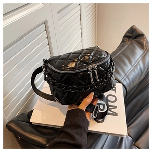 Detail of black quilted leather fanny pack with silver zippers and chain strap