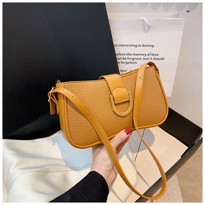 Detail einer gelben Lederhandtasche mit Kieselmaserung, U-Schnalle und dünnem Riemen