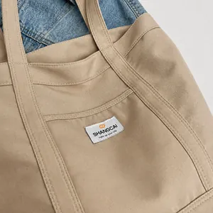 Primer plano del bolso tote de lona caqui con textura resistente y detalle de etiqueta