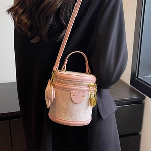 Pink embossed bucket bag with gold padlock and leather handle worn by a model