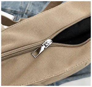 Detalle de la cremallera de metal plateado en el bolso de lona caqui con costuras