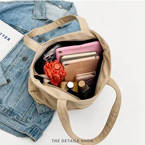 Vista interior que muestra la gran capacidad del bolso tote de lona caqui con varios objetos