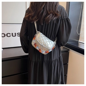 Detail of silver quilted crossbody bag with vibrant acrylic chain and dual zippers