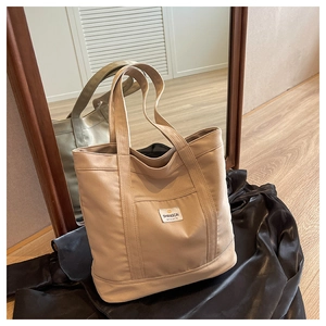 Detailed view of khaki canvas tote bag with front pocket and woven SHANGCAI label
