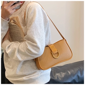 Detailansicht der ingwergelben Tasche mit Litschiprägung und goldener D-Ring-Schnalle