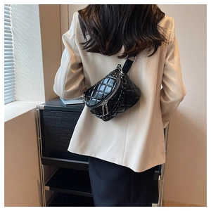 Close-up of black quilted crossbody bag with dual silver zippers and chain detail