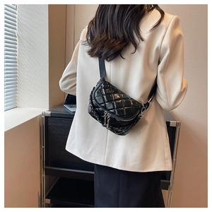 Detail of black quilted crossbody bag with glossy finish and chunky chain decoration