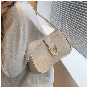 Seitenansicht der cremefarbenen Krokodilleder-Achseltasche mit U-Schnalle an einem Modell