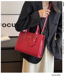 Détail du sac à main matelassé rouge avec lettrage doré et pendentif cœur sur mannequin