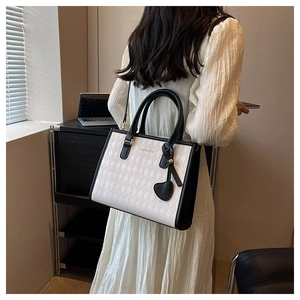 Détail du sac cabas matelassé blanc avec bordure noire et pendentif en forme de cœur