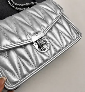 Detail view of metallic silver quilted bag featuring V-stitch and silver twist lock