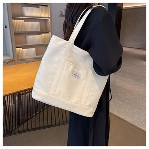 Detail of canvas tote bag with outer pocket and brand label in library setting
