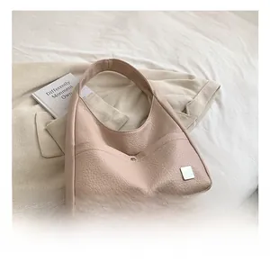 Close-up of pink hobo shoulder bag with lychee grain texture and metal square hardware