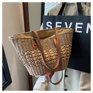 Detail of the woven straw tote bag with brown leather handles and textured fiber pattern