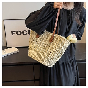 Detailed shot of straw tote bag with brown leather handles and hollow weave texture