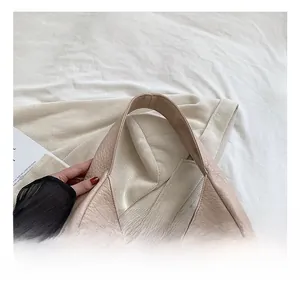 Detailed close-up of a beige faux leather bucket bag featuring a soft wide handle and fine stitching