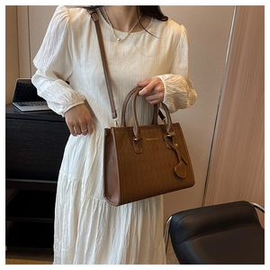 Sac fourre-tout marron matelassé avec bandoulière amovible et breloque cœur sur un mannequin