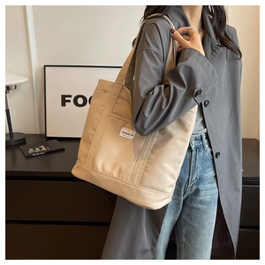 Detail view of the beige canvas tote bag with side pocket and brand label for women