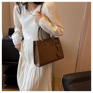Sac fourre-tout matelassé marron présenté dans un bureau avec un pendentif en cœur