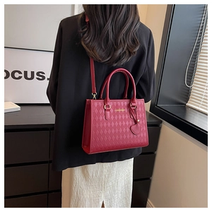 Modèle portant un sac cabas rouge matelassé avec charme cœur et bandoulière réglable