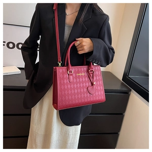 Détail d'un sac fourre-tout rouge matelassé avec charme de cœur et texte sur bandoulière