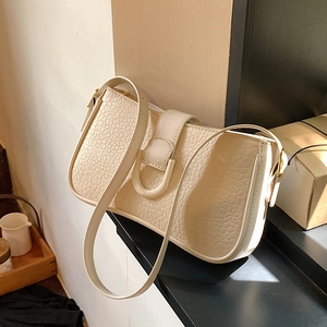 Cremeweiße strukturierte Leder-Schultertasche mit U-Schnalle auf einer Treppe