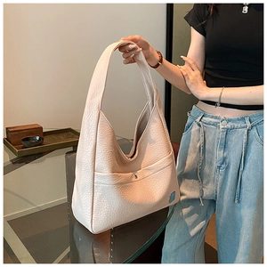 Detail of the high-quality lychee texture leather and snap button pocket on a beige hobo bag