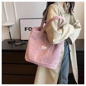Shoulder shot of a large pink canvas tote bag with white label for daily commute
