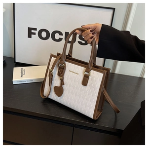 Détail de la texture tressée et lettrage doré sur le sac fourre-tout marron et blanc