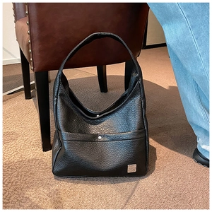 Close-up of black lychee grain leather hobo bag with wide strap and silver metal logo
