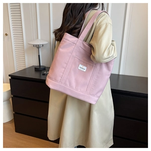 Detail view of pink canvas tote bag showing reinforced seams and branded fabric label