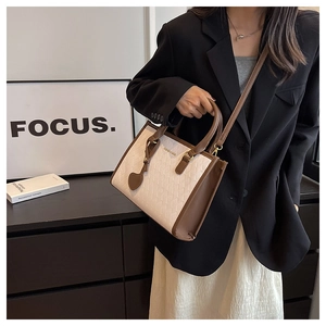 Détail du sac cabas crème avec garniture en cuir marron et texture matelassée sur modèle