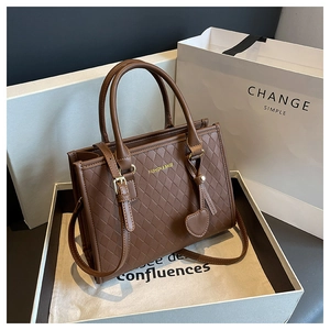 Détail d'un cabas matelassé marron avec breloque cœur sur une boîte cadeau de luxe