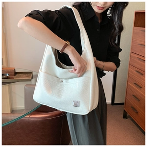 Detailed close-up of a white leather tote bag with lychee texture and metal button pocket