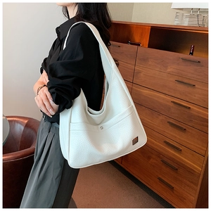 Close-up of white lychee leather tote bag featuring a front pocket and metallic plate detail