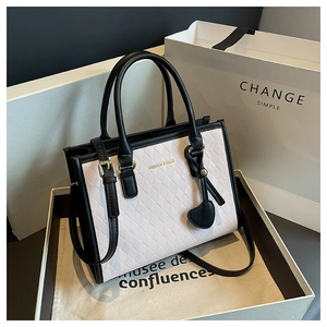 Détail du sac cabas matelassé avec lettrage doré et charme cœur dans une boîte cadeau
